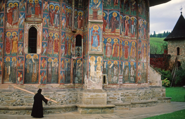 A nun taps a mallet against a wooden semantron, calling faithful to prayer in Bucovina, Romania. Photo credit: Peter Guttman