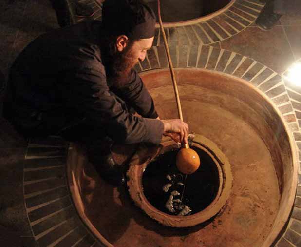A Georgian winemaker dips into a qvevri, demonstrating a UNESCO-listed ancient method of making wine. Photo credit: John Wurdeman