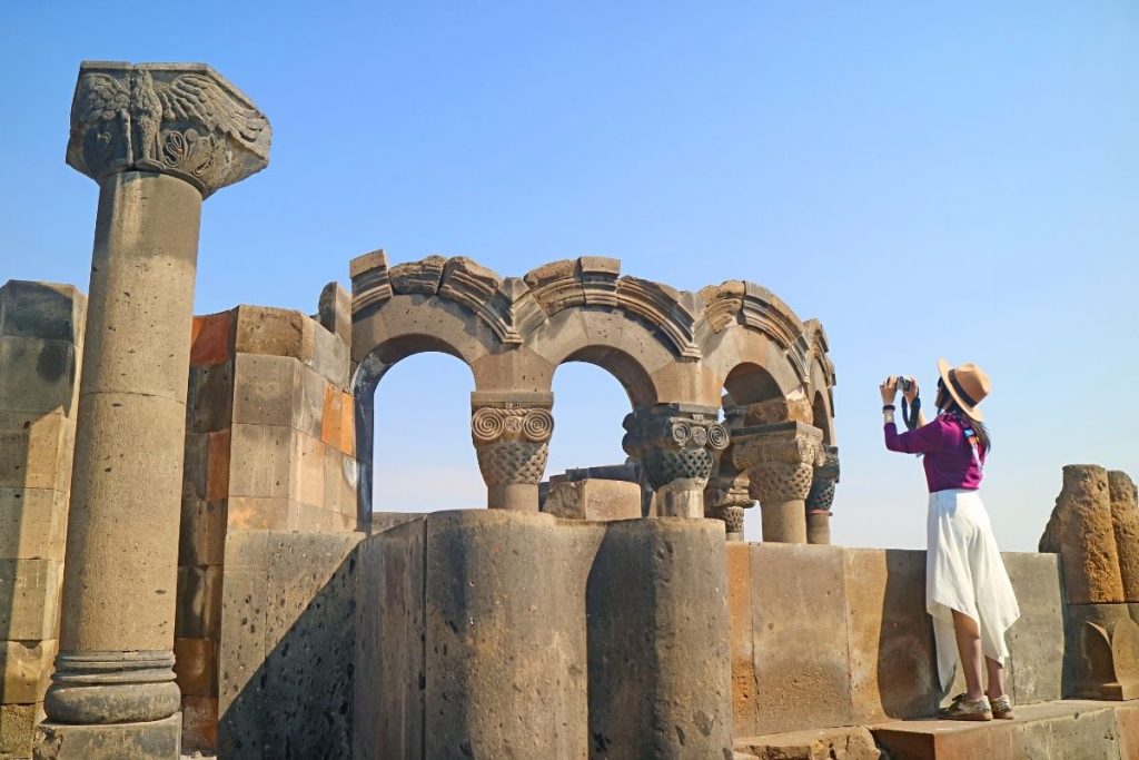 A traveler capturing the ancient ruins in Armenia with a camera. Image by MIR Corporation.

