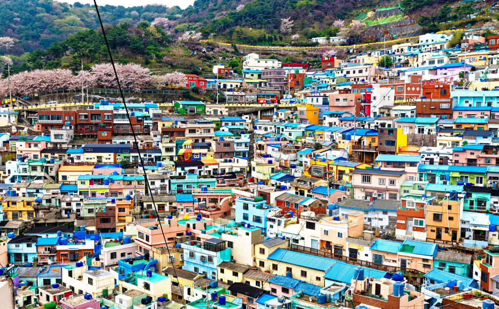 A stunning view of Busan’s colorful Gamcheon Culture Village with the cityscape and mountains in the background.